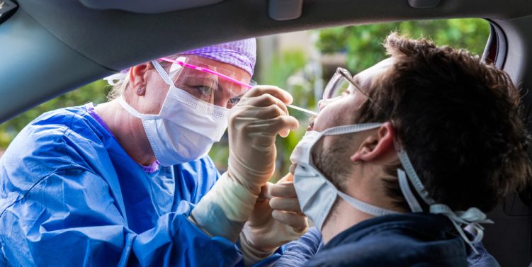 operatrice sanitaria che esegue un tampone a un uomo in auto